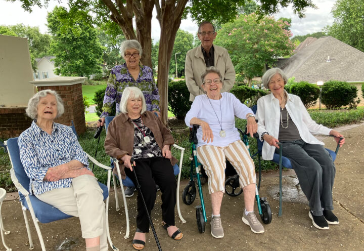 Group of Seniors Smiling and Enjoying the Outdoors of an Assisted Living Facility Group of Seniors Smiling and Enjoying the Outdoors of an Assisted Living Facility