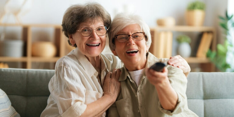 Two Elderly Women Watching Television Together on a Sofa at an Assisted Living Facility