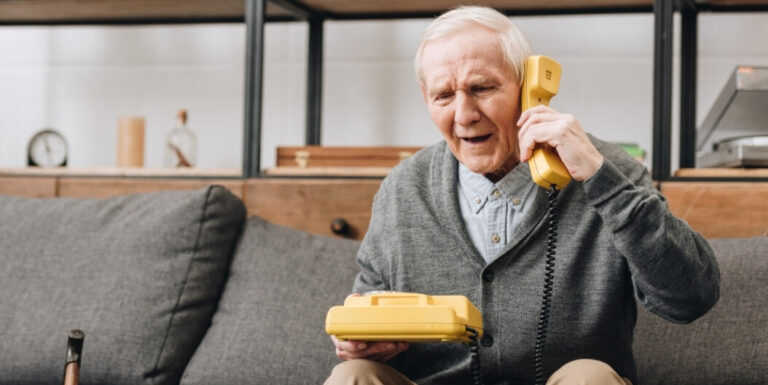 Elderly Man Using a Telephone with Hearing Support at Assisted Living Facility